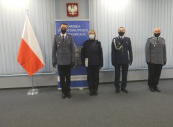 Na zdjęciu widać stojących obok siebie, przodem, trzech umundurowanych policjantów oraz umundurowaną policjantkę. Po lewej stronie znajduje się Flaga Polski, w tle baner z napisem Komenda Powiatowa Policji w Wadowicach.