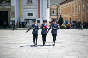 trzech policjantów przechodzi przez plac