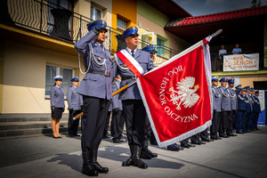 Poczet sztandarowy, trzech policjantów, z których jeden trzyma sztandar. W tle policjanci.