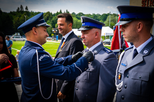 Policjant odznaczający jednego z dwóch stojących policjantów. Po prawej stronie Wójt Gminy Stryszów.