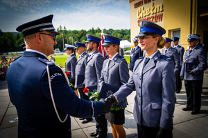 Zastępca Komendanta Wojewódzkiego Policji w Krakowie podający rękę stojącej w szeregu policjantce. W tle policjanci.