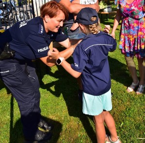 Umundurowana policjantka i mała dziewczynka ubrana w koszulę i czapkę policyjną,