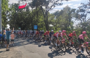 Jadący rowerzyści i kibice w rejonie drogi.