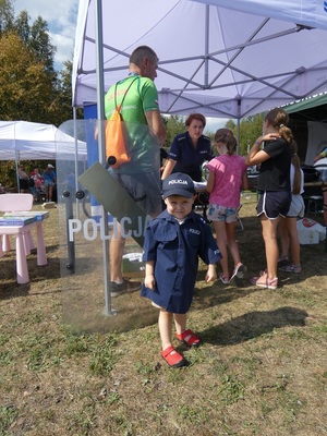 Chłopiec przebrany w mundur policjanta na tle stoiska policyjnego