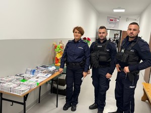 Umundurowani policjanci przy stoisku z ulotkami informacyjnymi