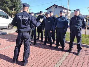 Stojący w dwuszeregu umundurowani policjanci, przed nimi stoi również umundurowany policjant