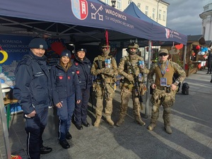 Na tle namiotu dwie policjantki i policjant oraz trzech przedstawicieli Wojska Obrony Terytorialnej.