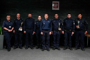Umundurowani policjantki i dwie policjanci. Osoby stoją obok siebie. Na ścianie Godło Polski.