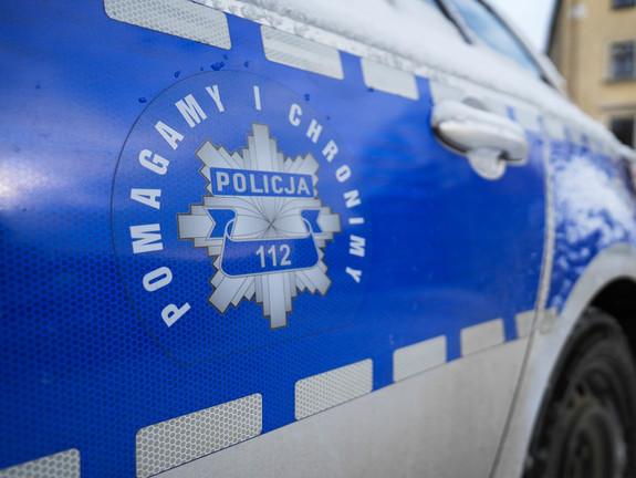 Boczna strona radiowozu. Na niebiskim tle odznaka policyjna z napisem Policja 112, wokoło napis Pomagamy i chronimy