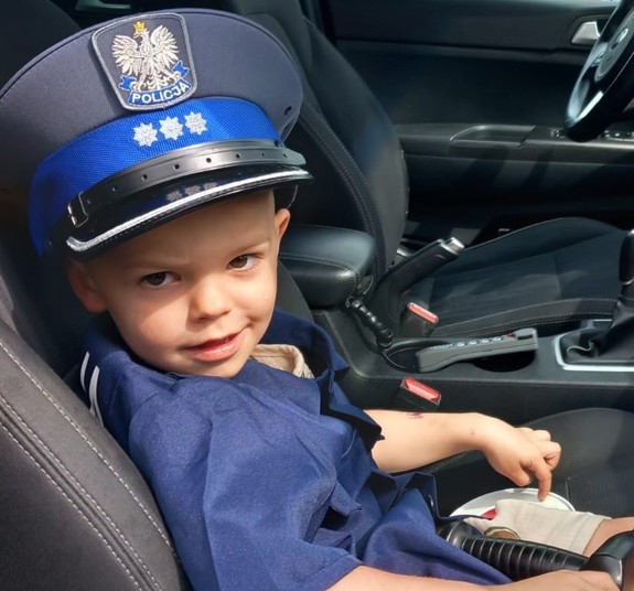 Mały chłopczyk ubrany w koszulę i czapkę policyjną
