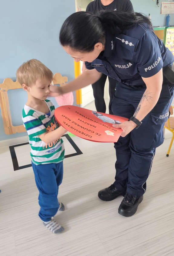 Na zdjęciu umundurowana policjantka i mały chłopczyk, który wręcza jej podziękowania.