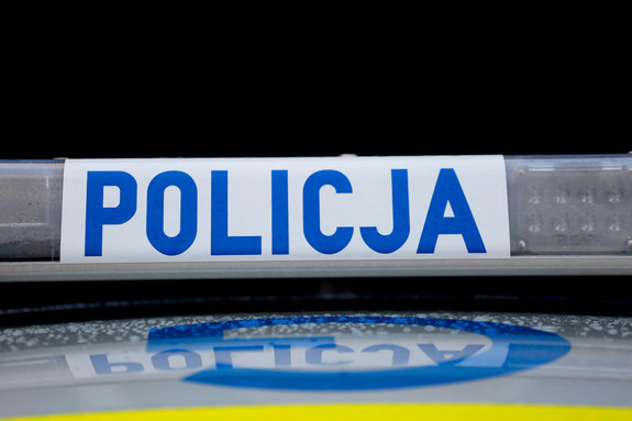Na białym tle napis Policja koloru niebieskiego, po prawej i lewej stronie światła