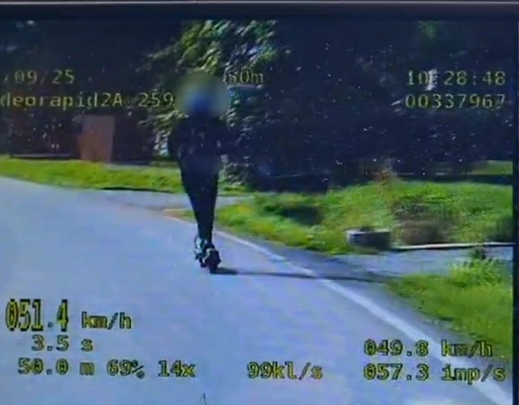 Zdjęcie z wideo rejestratora, na którym widać chłopaka jadącego na hulajnodze elektrycznej i zarejestrowana prędkość 51 kilometrów na godzinę.