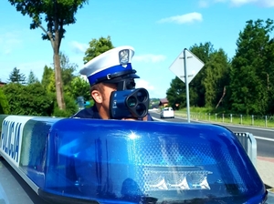 Policjant ruchu drogowego mierzący prędkość przy użyciu policyjnego miernika prędkości