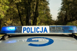 Sygnały świetlne i dźwiękowe na dachu pojazdu. Na białym tle niebieski napis Policja, po prawej i lewej stronie światła koloru niebieskiego