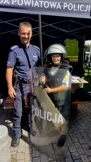 Policjant i chłopiec ubrany w elementy wyposażenia policyjnego