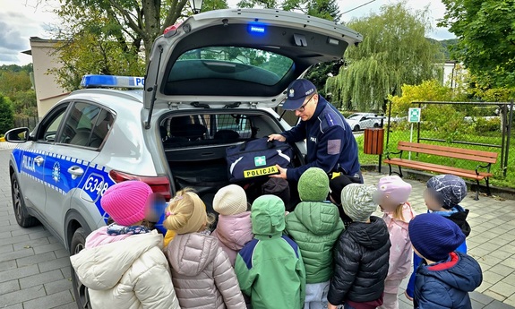 Policjant prezentujący dzieciom policyjny sprzęt, radiowóz