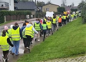 Grupa dzieci w kamizelkach odblaskowych idących po chodniku.