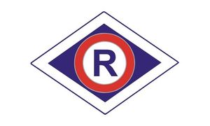 Logo ruchu drogowego. W białym rombie znajduje się mniejszy granatowy romb wewnątrz którego w kole koloru białego z czerwona lamówka jest Granatowa litera R