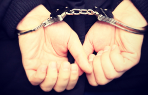 Policyjne kajdanki na rękach trzymanych z tyłu