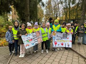 Dzieci w kamizelkach odblaskowych trzymające transparenty