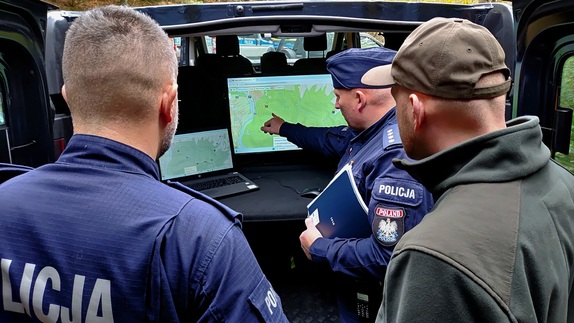 Dwóch policjantów i leśniczy patrzący w ekran z mapą