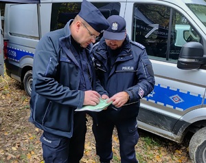 Dwóch umundurowanych policjantów patrzących w mapę