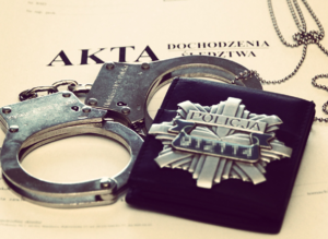 Na aktach sprawy policyjne kajdanki i odznaka policyjna