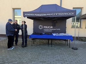 Namiot policyjny, a przy nim policjantka i policjant oraz mężczyzna.