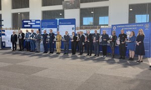 Przedstawiciele służb mundurowych, władz samorządowych, szkoły, którzy stoją obok siebie. W tle banery,