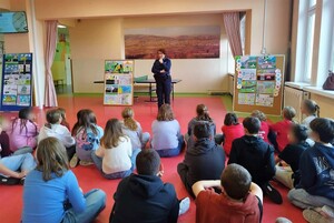 Umundurowana policjantka, a przed nią siedzące na podłodze dzieci.