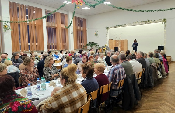 Na scenie policjantka, przed nią przy stolikach grupy osób