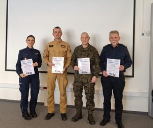 Na zdjęciu od lewej policjantka, strażak, żołnierz i strażnik miejski. Każda z osób w rękach trzyma dyplom.