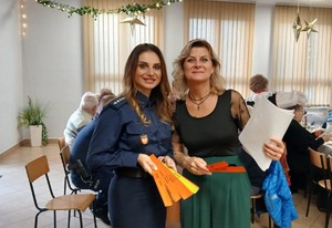 Na zdjęciu policjantka i kobieta w stroju cywilnym. W tle osoby siedzące przy stolikach.