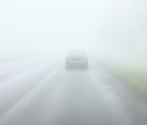 Pojazd jadący po drodze podczas mgły, który nie ma włączonych świateł.