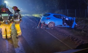 Rozbity samochód osobowy, po lewej strażacy.