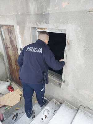 Umundurowany policjant zaglądający przez okno w opuszczonym budynku