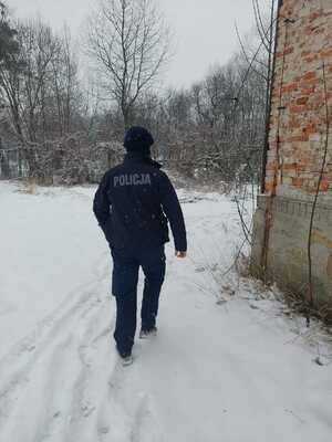 Policjant idący obok opuszczonego budynku