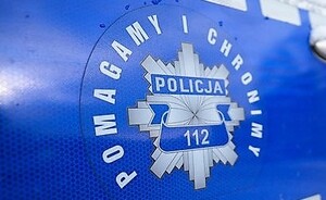 Na niebieskim tle odznaka policyjna z napisem Policja 112, wokoło napis Pomagamy i Chronimy.