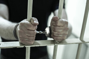 Osoba za kratami. Ma założone kajdanki