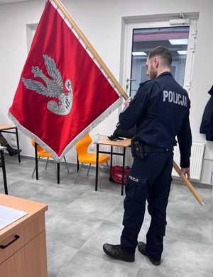 Umundurowany policjant trzymający sztandar