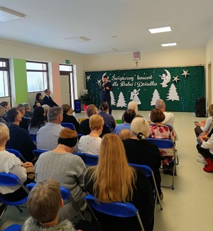 Policjant, a przed nimi osoby siedzące na krzesłach