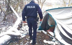 Umundurowany policjant tyłem sprawdzający miejsce przebywania osób bezdomnych