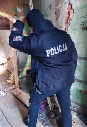 Umundurowany policjant sprawdzający pomieszczenie pustostanu