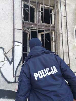 Policjant zerkający przez okno opuszczanego budynku