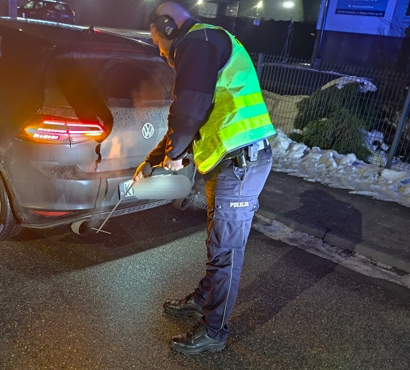 Policjant ruchu drogowego, który przy użyciu sonometru mierzy poziom hałasu w pojeździe