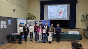 Na tle banerów grupa osób, w tym dzieci, policjanci i mężczyźni.