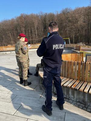 Na zdjęciu umundurowany policjant i dwie dziewczyny w mundurach wojskowych