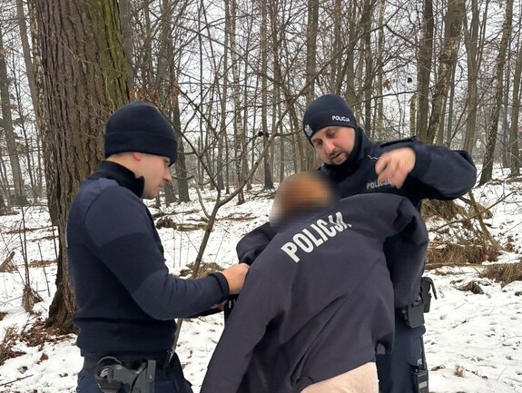 Dwóch policjantów okrywających policyjna kurtką odnalezioną dziewczynę