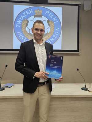 Policjant w stroju cywilnym trzymający w ręku dyplom